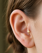 A tiny crown adds a playful statement detail while staying compact enough for everyday styling. Made for fully healed tragus piercings, it adds a compact decorative detail without turning the piece into a dangling design. Handmade to order in 14ct solid gold, it fits naturally with playful, symbolic and statement-led styling rather than reading as a generic plain hoop.