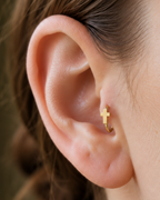 A polished cross gives the hoop a clean symbolic detail without stones, enamel or dangling parts. Made for fully healed tragus piercings, it adds a compact decorative detail without turning the piece into a dangling design. Handmade to order in 14ct solid gold, it fits naturally with clean, symbolic and understated styling rather than reading as a generic plain hoop.