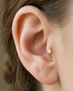 A small square motif gives the hoop a crisp, graphic finish while keeping the overall design minimal. Made for fully healed tragus piercings, it adds a compact decorative detail without turning the piece into a dangling design. Handmade to order in 14ct solid gold, it fits naturally with crisp, geometric and minimal styling rather than reading as a generic plain hoop.