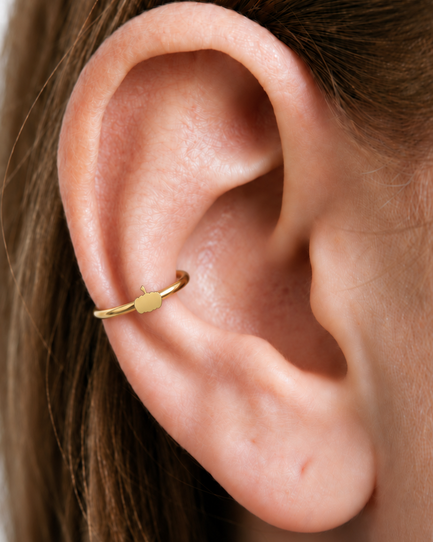 A tiny pumpkin adds an autumn and Halloween note while keeping the piece polished and wearable. Made for fully healed conch piercings, it pairs the larger hoop silhouette of a conch ring with a small fixed motif for a more distinctive ear stack. Handmade to order in 14ct solid gold, it fits naturally with autumnal, festive and Halloween-led styling rather than reading as a generic plain hoop.