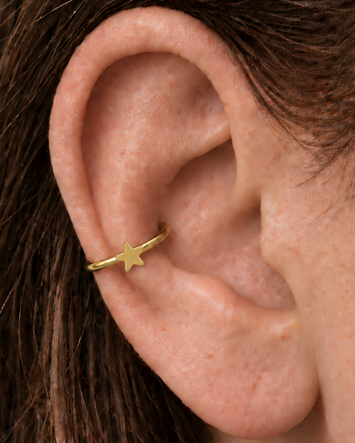 A crisp little star adds a bright celestial point to an otherwise minimal gold hoop. Made for fully healed conch piercings, it pairs the larger hoop silhouette of a conch ring with a small fixed motif for a more distinctive ear stack. Handmade to order in 14ct solid gold, it fits naturally with bright, celestial and playful styling rather than reading as a generic plain hoop.