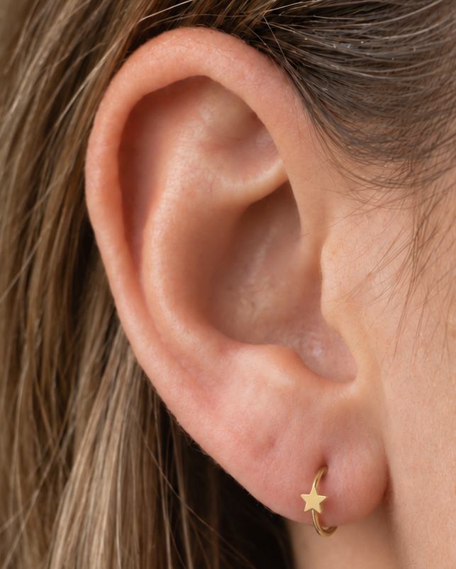 A crisp little star adds a bright celestial point to an otherwise minimal gold hoop. Made for fully healed lobe piercings and sold individually, it works easily in first, second or third-lobe stacks. Handmade to order in 14ct solid gold, it fits naturally with bright, celestial and playful styling rather than reading as a generic plain hoop.