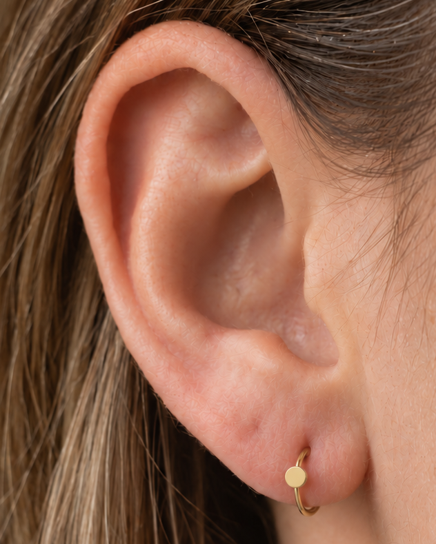 A simple circle motif keeps the design pared back, rounded and easy to mix with other jewellery. Made for fully healed lobe piercings and sold individually, it works easily in first, second or third-lobe stacks. Handmade to order in 14ct solid gold, it fits naturally with simple, rounded and minimal styling rather than reading as a generic plain hoop.