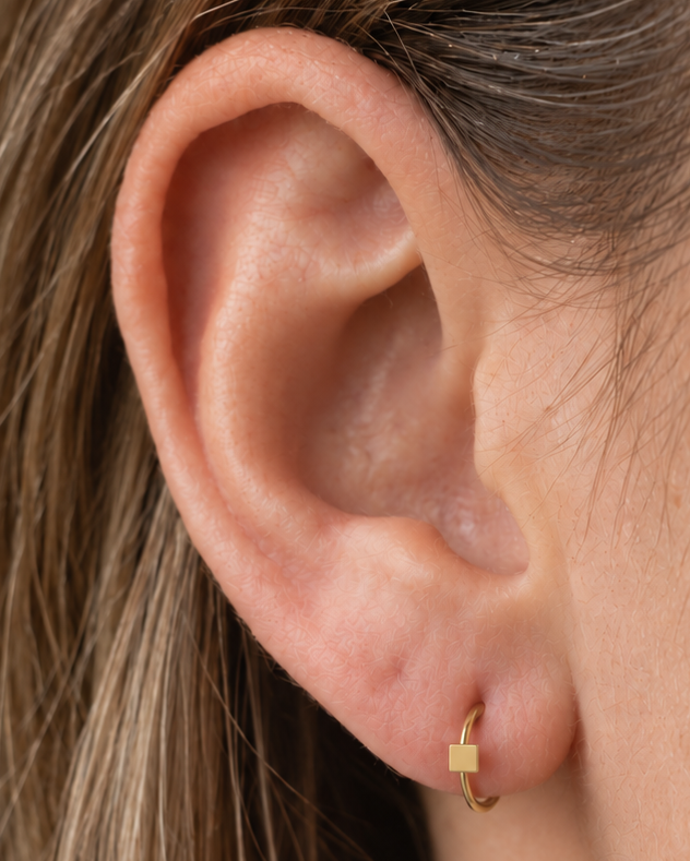 A small square motif gives the hoop a crisp, graphic finish while keeping the overall design minimal. Made for fully healed lobe piercings and sold individually, it works easily in first, second or third-lobe stacks. Handmade to order in 14ct solid gold, it fits naturally with crisp, geometric and minimal styling rather than reading as a generic plain hoop.