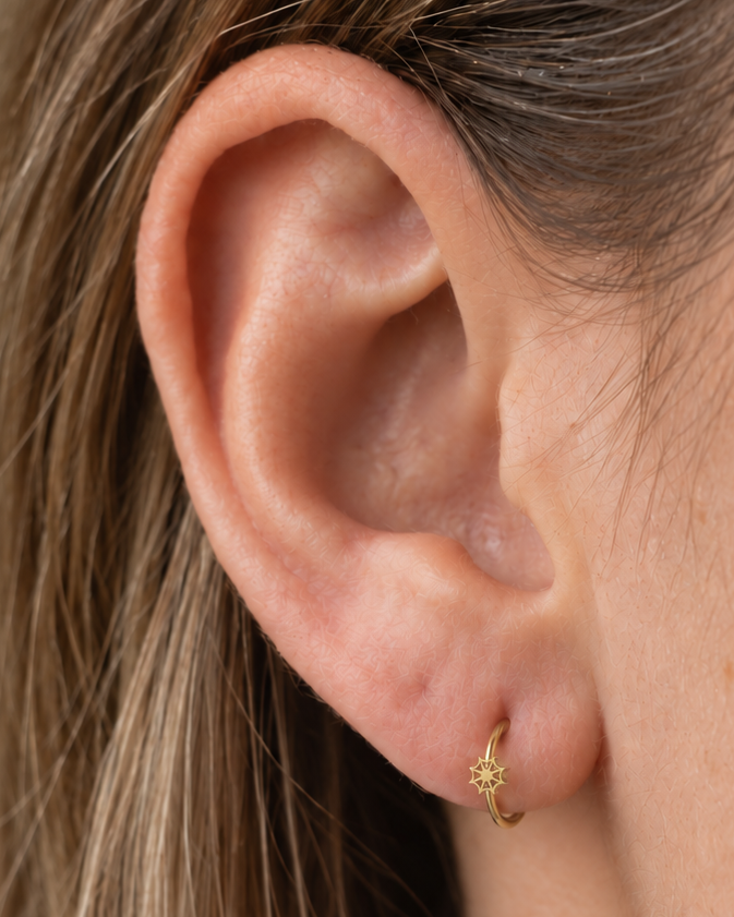 An openwork spider web adds a graphic Halloween detail with visible negative space and a light feel. Made for fully healed lobe piercings and sold individually, it works easily in first, second or third-lobe stacks. Handmade to order in 14ct solid gold, it fits naturally with graphic, spooky and Halloween-led styling rather than reading as a generic plain hoop.