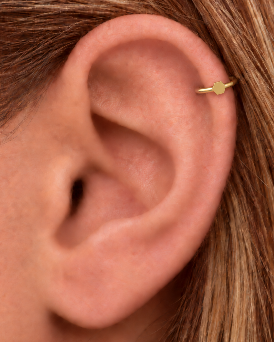 A polished hexagon adds a structured geometric accent that still feels easy to wear. Made for fully healed helix piercings, it keeps the profile compact for an upper-ear stack while leaving the motif clearly visible. Handmade to order in 14ct solid gold, it fits naturally with structured, geometric and modern styling rather than reading as a generic plain hoop.
