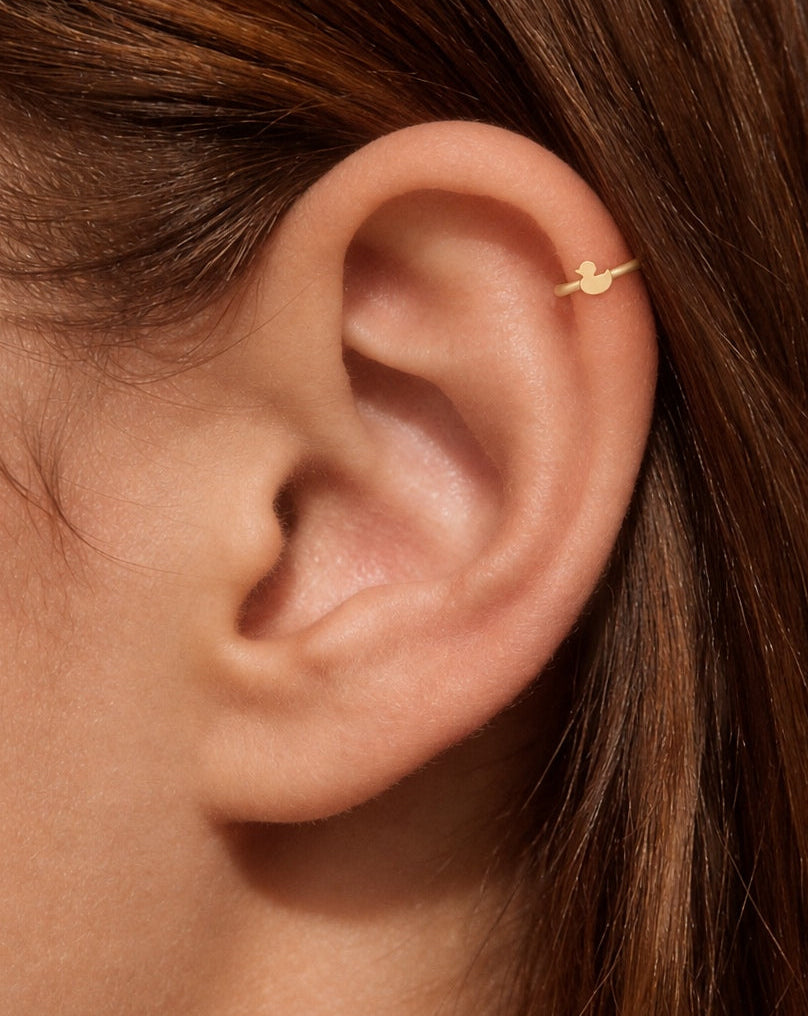 This miniature duck is shown in profile, with a round head, a small projecting bill and a curved body that ends in an upturned tail. Its smooth, polished surface has no engraved eyes, wing patterns or gemstones, keeping the silhouette simple and clear.

Handmade to order in nickel-free 14ct solid gold, this duck helix hoop is available in yellow, white or rose gold. Choose a 5, 6 or 7mm internal diameter and 18G (1.0mm) or 20G (0.8mm). The motif measures approximately 3mm. Designed for fully healed helix pi