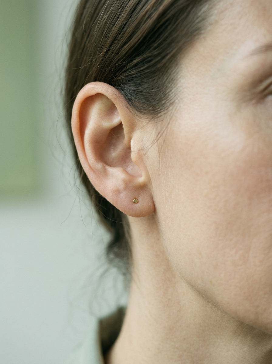 A fully healed Tragus piercing wearing a tiny motif hoop near the ear canal
