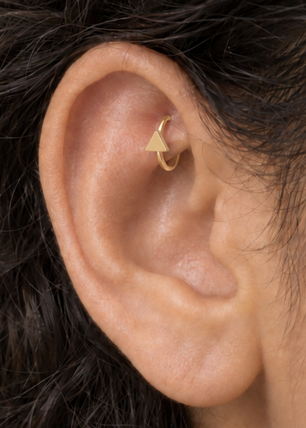 A small triangle gives the hoop a sharper geometric detail with a clean modern feel. Made for fully healed traditional rook piercings, it gives a small curved ear placement a clear motif-led detail while keeping the hoop clean and wearable. Handmade to order in 14ct solid gold, it fits naturally with clean, geometric and modern styling rather than reading as a generic plain hoop.