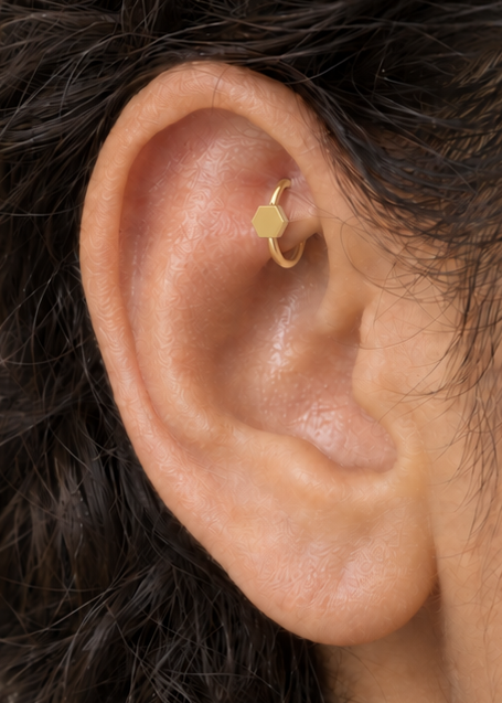 A polished hexagon adds a structured geometric accent that still feels easy to wear. Made for fully healed traditional rook piercings, it gives a small curved ear placement a clear motif-led detail while keeping the hoop clean and wearable. Handmade to order in 14ct solid gold, it fits naturally with structured, geometric and modern styling rather than reading as a generic plain hoop.