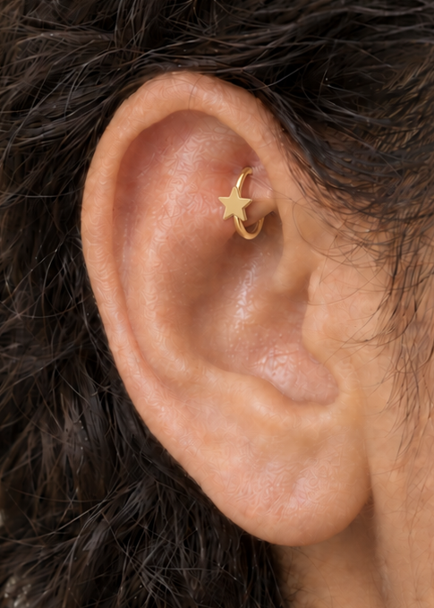 A crisp little star adds a bright celestial point to an otherwise minimal gold hoop. Made for fully healed traditional rook piercings, it gives a small curved ear placement a clear motif-led detail while keeping the hoop clean and wearable. Handmade to order in 14ct solid gold, it fits naturally with bright, celestial and playful styling rather than reading as a generic plain hoop.