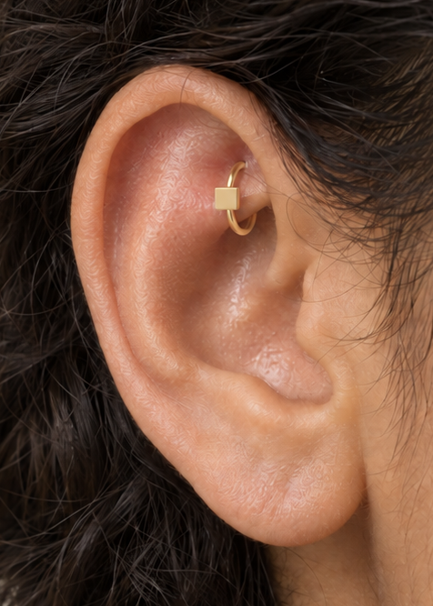 A small square motif gives the hoop a crisp, graphic finish while keeping the overall design minimal. Made for fully healed traditional rook piercings, it gives a small curved ear placement a clear motif-led detail while keeping the hoop clean and wearable. Handmade to order in 14ct solid gold, it fits naturally with crisp, geometric and minimal styling rather than reading as a generic plain hoop.