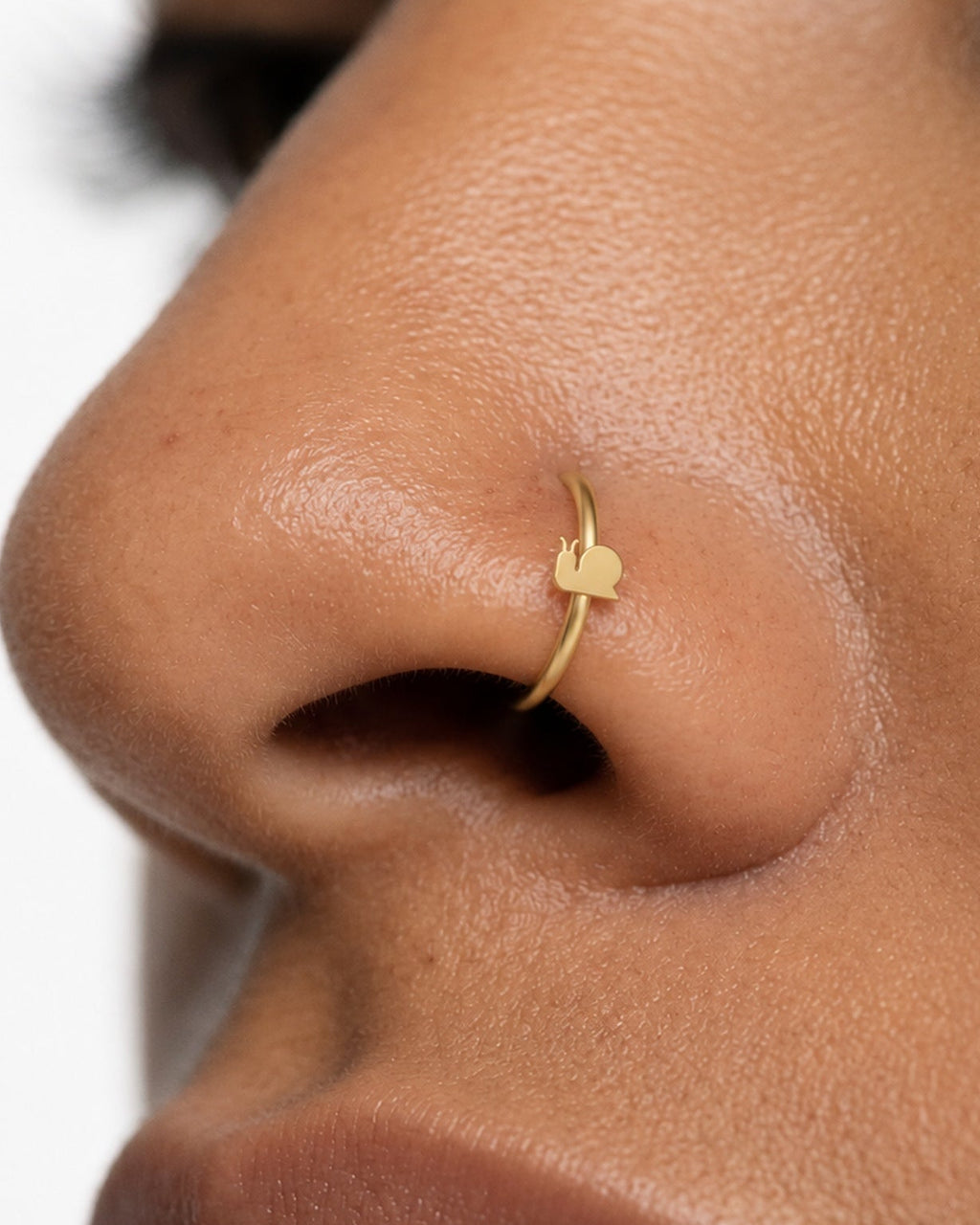 A little garden character for your everyday jewellery. This 14ct solid gold snail nostril ring pairs an approximately 3mm polished snail silhouette with a smooth seamless hoop. A rounded shell, low body and two curved feelers define the design, with no engraved spiral or gemstones.
Handmade to order in yellow, white or rose gold, with inner diameters from 6 to 10mm and a choice of 18G (1.0mm) or 20G (0.8mm). Both the snail and hoop are solid gold and nickel-free, designed for a fully healed nostril piercing