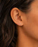 A distinctive 14ct solid gold crown huggie hoop with an open design for easier fitting. No twisting or end alignment required — simply guide the smooth end through your fully healed nose or ear piercing and rotate it into position.