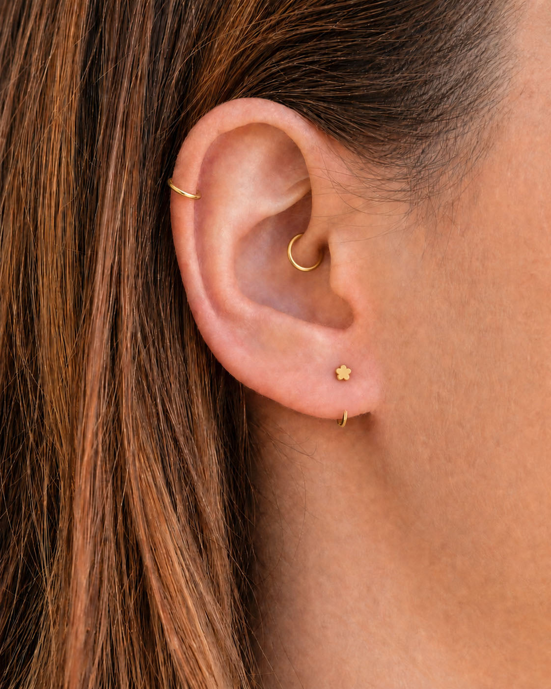 A delicate 14ct solid gold flower huggie hoop with an open design for easier fitting. No twisting or end alignment required — simply guide the smooth end through your fully healed nose or ear piercing and rotate it into position.