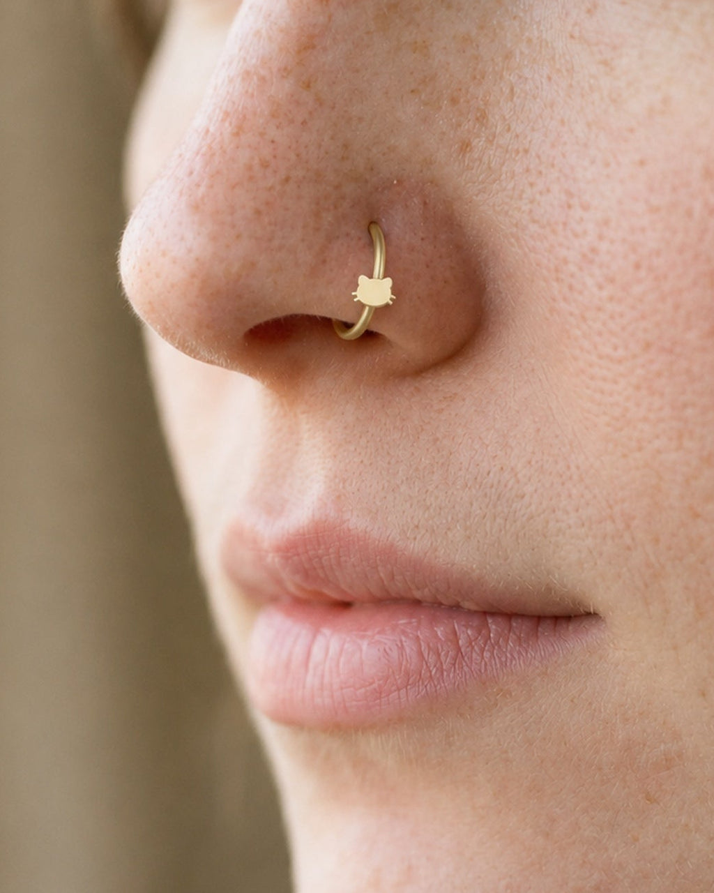 Two little ears and a few whiskers give this hoop its feline character. This 14ct solid gold cat head nostril ring pairs an approximately 3mm polished cat-face silhouette with a smooth seamless hoop. The rounded face is left plain, allowing the ears and whiskers to define the design.
Handmade to order in yellow, white or rose gold, with inner diameters from 6 to 10mm and a choice of 18G (1.0mm) or 20G (0.8mm). Both the cat head and hoop are solid gold and nickel-free, designed for a fully healed nostril pie