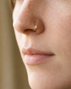 This miniature snowflake has six arms radiating from a solid centre, each with small branches and rounded ends. The spaces between the arms define the shape, while the smooth gold surface keeps the design simple. There are no gemstones or engraved details.

Handmade to order in nickel-free 14ct solid gold, this snowflake nostril hoop is available in yellow, white or rose gold. Choose a 6, 7, 8, 9 or 10mm internal diameter and 18G (1.0mm) or 20G (0.8mm). The motif measures approximately 3mm. Designed for ful
