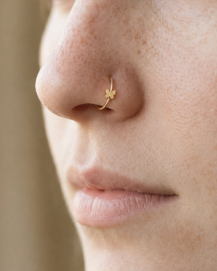 A delicate butterfly detail for your everyday jewellery. This 14ct solid gold butterfly nostril ring pairs an approximately 3mm polished butterfly silhouette with a smooth seamless hoop. Larger upper wings and smaller rounded lower wings create a soft, simple outline, with no gemstones or engraved decoration.
Handmade to order in yellow, white or rose gold, with inner diameters from 6 to 10mm and a choice of 18G (1.0mm) or 20G (0.8mm). Both the butterfly and hoop are solid gold and nickel-free, designed for