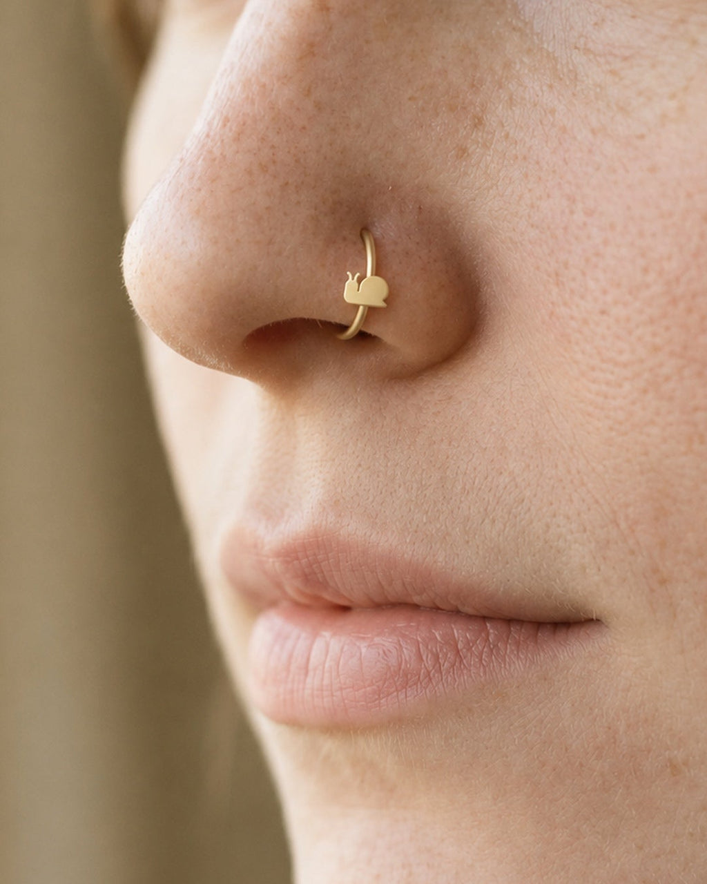 A little garden character for your everyday jewellery. This 14ct solid gold snail nostril ring pairs an approximately 3mm polished snail silhouette with a smooth seamless hoop. A rounded shell, low body and two curved feelers define the design, with no engraved spiral or gemstones.
Handmade to order in yellow, white or rose gold, with inner diameters from 6 to 10mm and a choice of 18G (1.0mm) or 20G (0.8mm). Both the snail and hoop are solid gold and nickel-free, designed for a fully healed nostril piercing